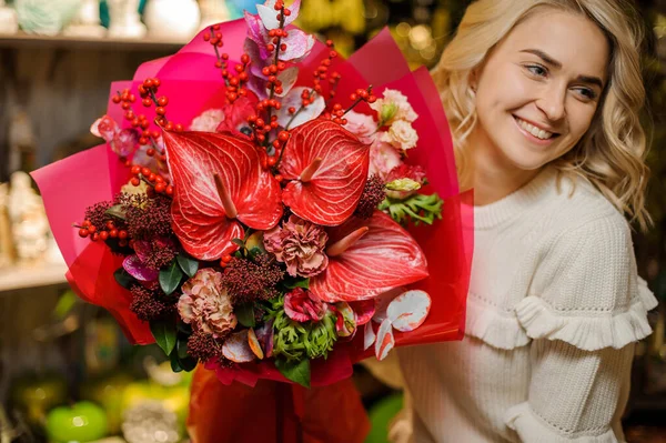 Heureuse femme tient beau bouquet rouge de différentes fleurs décorées avec du papier d'emballage. — Photo