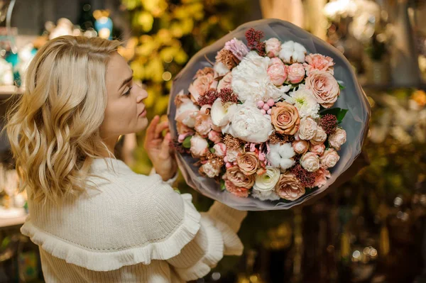 Precioso ramo de rosas y peonías envueltas en papel en las manos de las mujeres — Foto de Stock