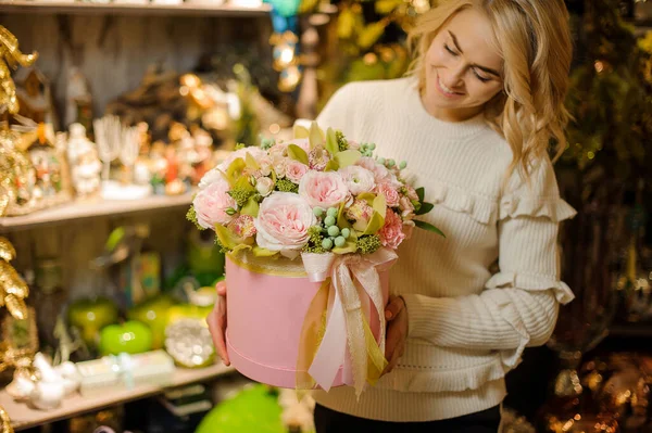 Linda composición de flores en caja redonda decorada con cinta rosa en las manos de la mujer. — Foto de Stock