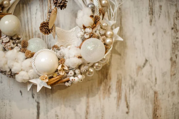 Zbliżenie świątecznego wieńca ozdobionego białymi kulkami, szyszkami sosnowymi, kijami cynamonowymi i kwiatami bawełny. — Zdjęcie stockowe