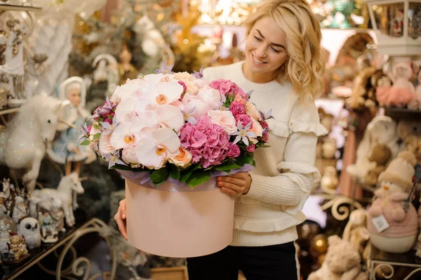 미소짓는 여인의 손에 둥근 분홍색 상자 속에 신선 한 꽃들이 우아 하게 조합되어 있는 모습 — 스톡 사진