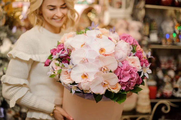 El primer plano de la composición de las flores frescas en la caja redonda rosada en las manos de la mujer sonriente —  Fotos de Stock