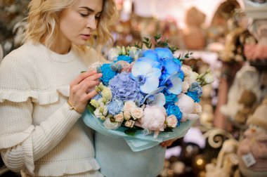 Mavi yuvarlak kutuda farklı çiçeklerle dolu güzel bir çiçek buketi.