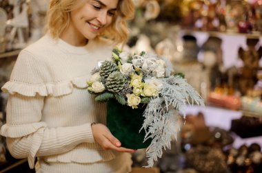 Gülümseyen bir kadının ellerinde yuvarlak yeşil kutuda yaratıcı yeni yıl kompozisyonu.