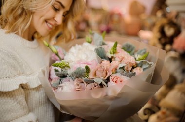 Bir buket ortanca, şakayık ve güller kağıda sarılmış kadınların ellerinde.