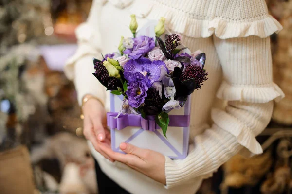 Arreglo floral creativo en caja cuadrada decorada con cinta en manos femeninas. — Foto de Stock