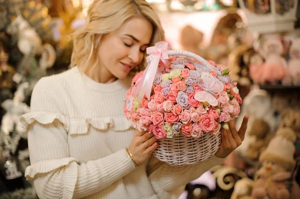 Cesta de vime branco com pequenas rosas cor-de-rosa no interior em mãos de jovem bela mulher loira — Fotografia de Stock