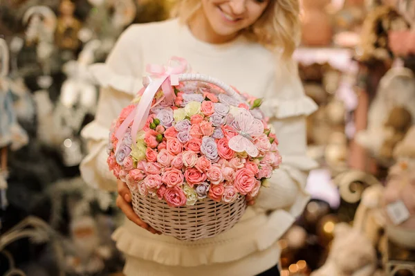 Se centran en delicada cesta de mimbre blanco con pequeñas rosas rosadas en el interior en manos de la mujer — Foto de Stock
