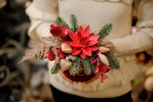 Közelkép a fényes virág elrendezése díszített arany karácsonyfa dekoráció a nők kezében. — Stock Fotó
