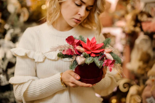 Φωτεινή δημιουργική διάταξη λουλουδιών διακοσμημένα με χρυσό χριστουγεννιάτικο δέντρο διακοσμήσεις στο χέρι των γυναικών. — Φωτογραφία Αρχείου