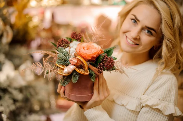 Hermoso arreglo floral brillante en caja redonda en manos de mujer rubia — Foto de Stock