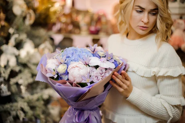 Lindo buquê de flores envolto em papel lilás nas mãos de mulher loira — Fotografia de Stock