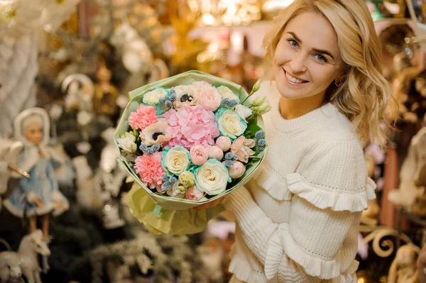 Mujer atractiva sosteniendo ramo de hortensias, rosas, peonías y claveles envueltos en papel — Foto de Stock