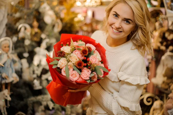 Ξανθιά γυναίκα κρατά όμορφο μπουκέτο από φρέσκα τριαντάφυλλα τυλιγμένο σε κόκκινο χαρτί. — Φωτογραφία Αρχείου