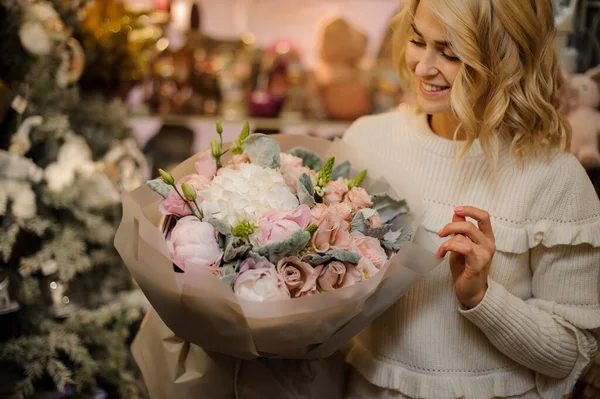 Весела блондинка тримає букет з гортензій і півоній і троянд, загорнуті в папір — стокове фото