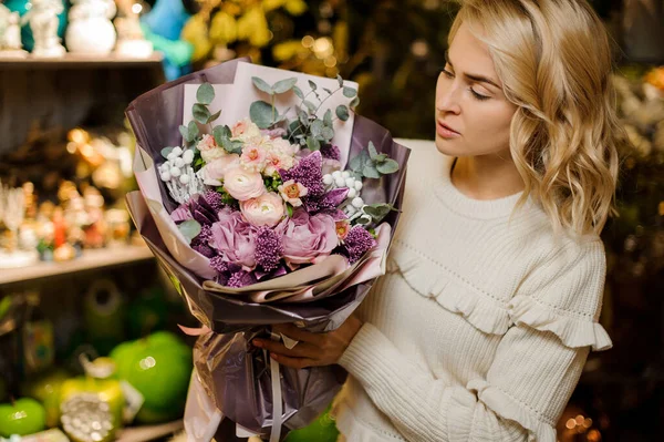 Lindo ramo de flores frescas en tonos lila, envuelto en papel decorativo en manos de las mujeres —  Fotos de Stock