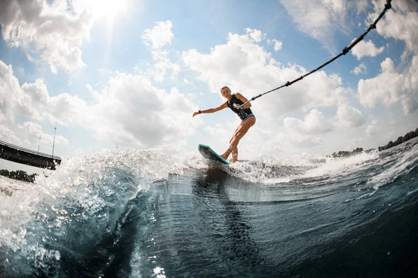 Mujer joven montando en el velorio surf celebración de la cuerda de la lancha — Foto de Stock