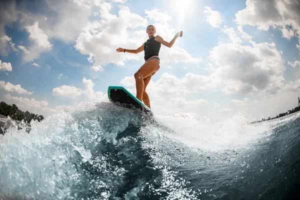 Stilig våt kvinna svart badväst rider uppför floden våg på wake board — Stockfoto