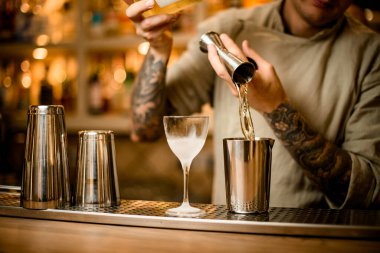 Barmen barın tezgahındaki bardağa metal jigger bardaktan su dökerken dikkatli ol.