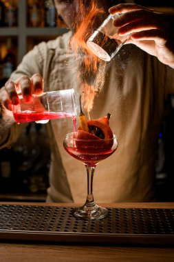 İnsan ustalıkla içine sebze konan malzemeler katar ve üzerine ateş yakar.