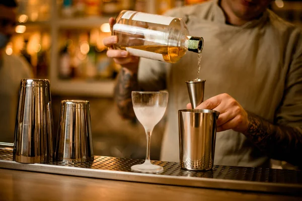 Bril staat op bar en in de achtergrond barman is gieten drankje in jigger — Stockfoto