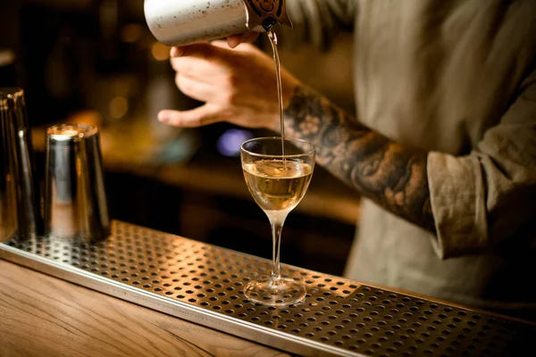 Homem barman cuidadosamente derramando coquetel pronto a partir de copo de medição em vidro no bar — Fotografia de Stock