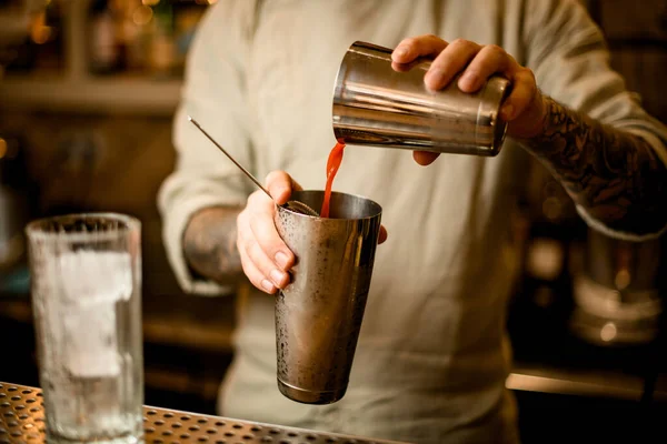 Camarero vierte jugo de tomate de un vaso de acero agitador en otro vaso — Foto de Stock