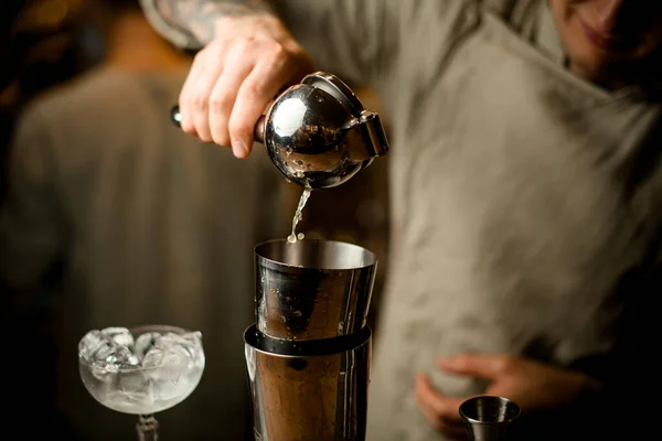 Hombre barman sostiene exprimidor de acero y con maestría exprime jugo en agitador — Foto de Stock