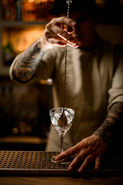 Чоловік бармен з довгою ложкою бару перемішайте кубики льоду в келиху вина — стокове фото