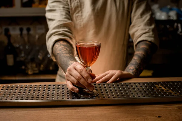 Camarero hombre suavemente sostiene copa de vino con bebida alcohólica que se encuentra en el mostrador de bar — Foto de Stock