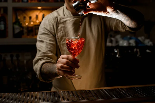 Camarero sostiene con copa de vino de mano con bebida brillante y precisa añade ingrediente de jigger — Foto de Stock