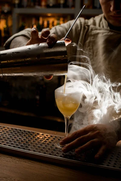 Vista de cerca del barman que vierte la bebida humeante de la taza del agitador en la copa de vino — Foto de Stock