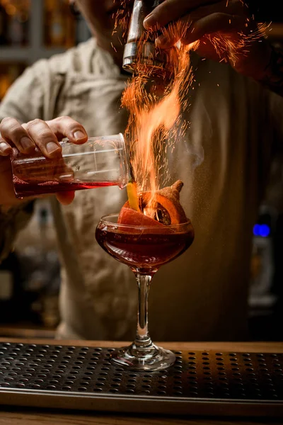 Barman añadir ingredientes al vidrio con calabaza y pimienta en el interior y hace fuego sobre él — Foto de Stock