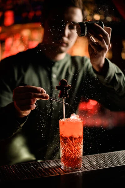 Barkeeper verziert Glas akkurat mit Cocktail mit Schokoladenbonbons und streut Puderzucker — Stockfoto