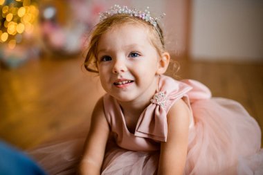 Saçında süsleme olan pembe elbiseli küçük şirin kızın yakın çekimi.