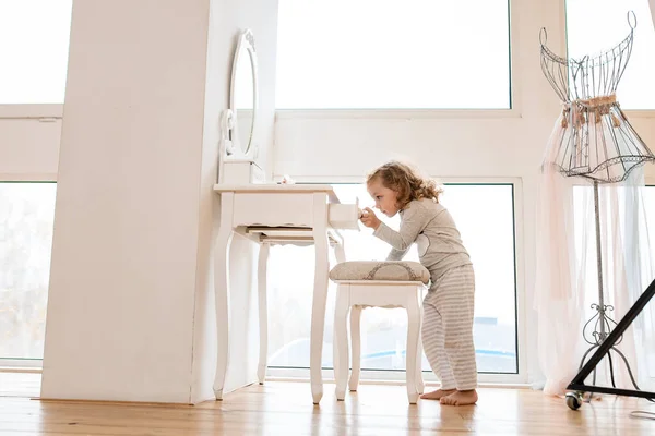 Hermosa niña está cerca de la consola con espejo y saca el cajón de ella — Foto de Stock