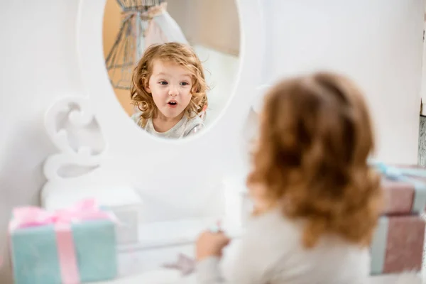 Reflejo en el espejo de la niña linda con expresión sorprendida en su cara — Foto de Stock