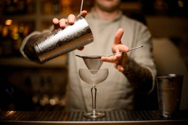 Erkek barmen şarap kadehinin üzerinde elek tutar ve kokteyl doldurmaya başlar.