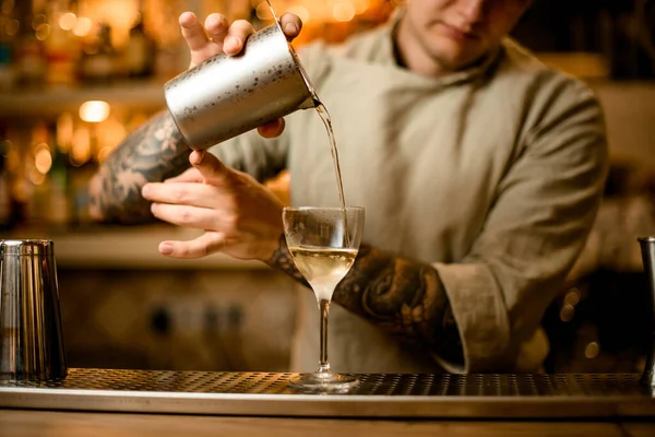 Вид чоловіка бармена, який наливає готовий коктейль з мірної чашки в склянку біля бару — стокове фото