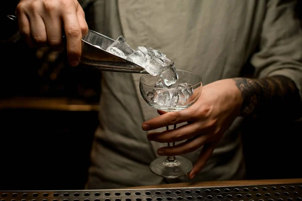 Чоловік бармен тримає металеву ложку з кубиками льоду і вливає їх у келих для вина — стокове фото