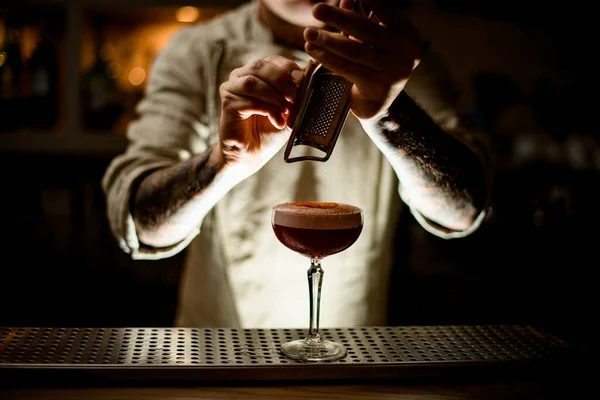 L'uomo a bar grate esatte la cannella sopra vetro di cocktail con schiuma — Foto Stock