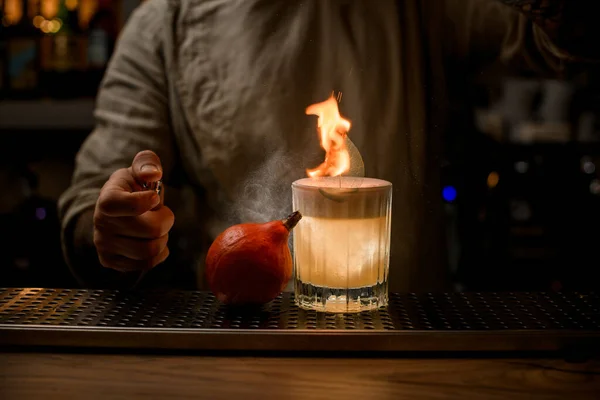Man accurate sprinkles on old fashioned glass of cocktail with foam and with burning leaf. — Stock Photo, Image