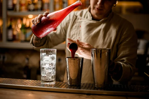 Camarero sostiene la botella en la mano y con otra mano vierte jugo de jigger en la coctelera — Foto de Stock
