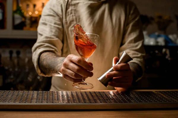 Άντρας μπάρμαν κρατά κοκτέιλ ποτήρι με πιτσίλισμα αλκοολούχο ποτό στο χέρι του — Φωτογραφία Αρχείου