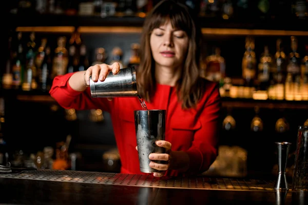 Primo piano delle mani del barista femminile che tengono i bicchieri dello shaker e versano liquido — Foto Stock