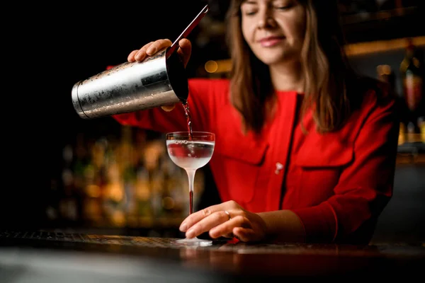 Θηλυκό μπάρμαν ρίχνει διαφανές ποτό από γυαλί χάλυβα σε παγωμένο γυαλί στο μετρητή μπαρ — Φωτογραφία Αρχείου