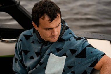 Kafkasyalı yetişkin bir adamın teknede oturup bakışlarını kaçırması.