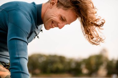 Uçan saçlı, gülümseyen genç adamın yan görünüşü