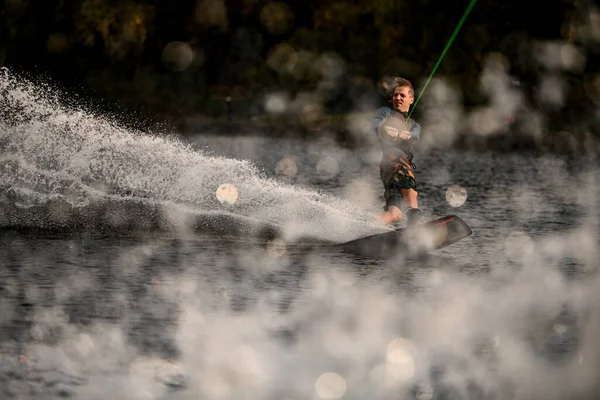 Jeune gars wakeboarder tient la corde dans ses mains et équilibre sur la vague — Photo