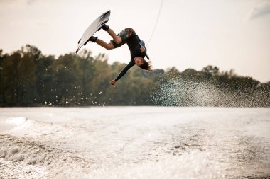 Wakeboard 'da eğlenen ekstrem bir adam nehir suyunun üzerinden atlıyor.